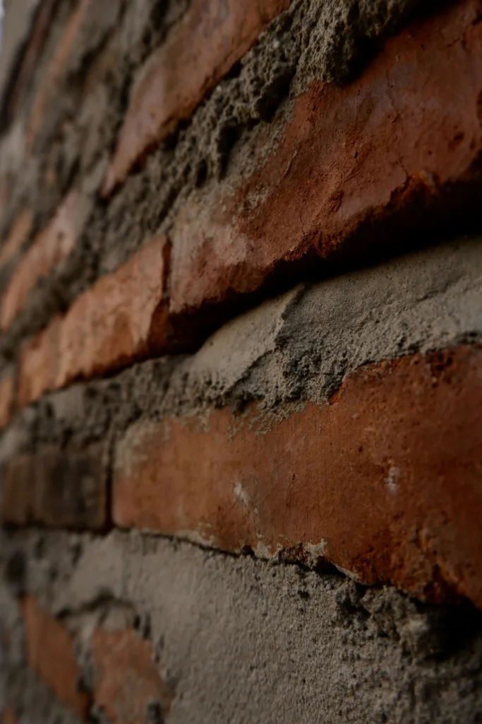 The side of a brick wall with uneven mortar.